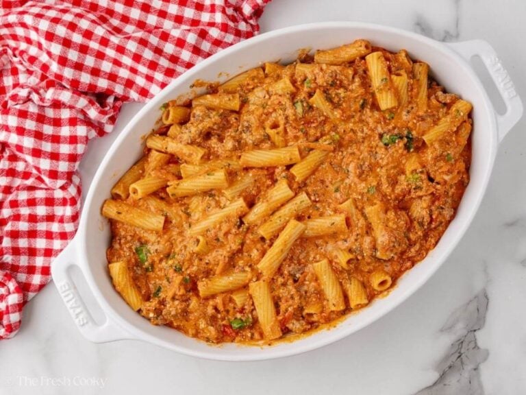 Rigatoni pasta with cheeses and herbs placed in a baking dish.