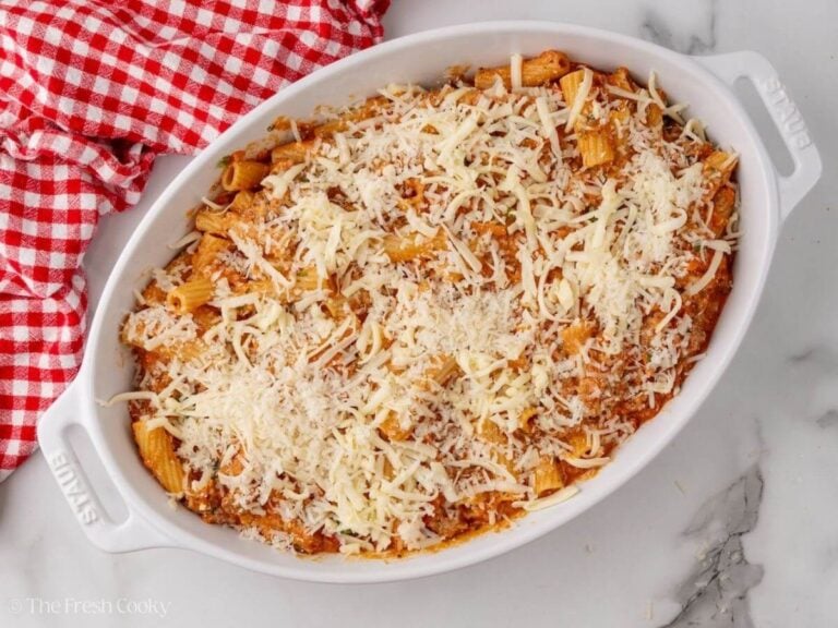 Rigatoni pasta topped with shredded mozzarella in a baking dish.