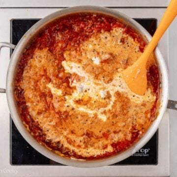 Heavy cream added to the tomato meat sauce in a skillet.