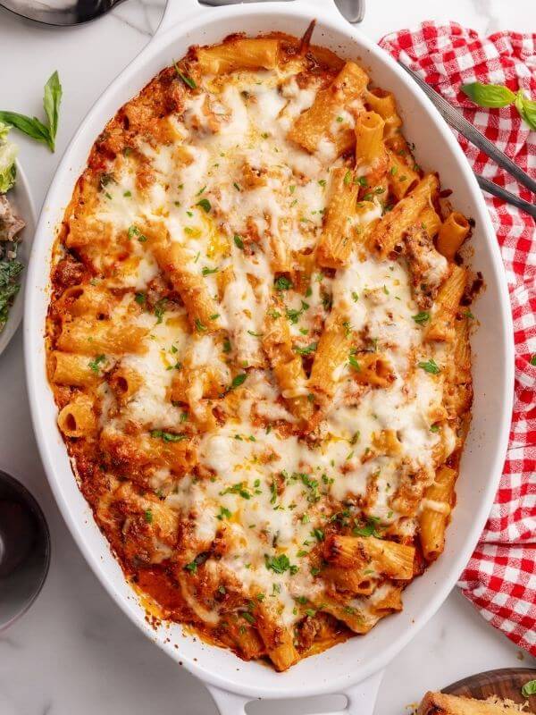 Staub oval baking dish filled with rich baked rigatoni bolognese. 