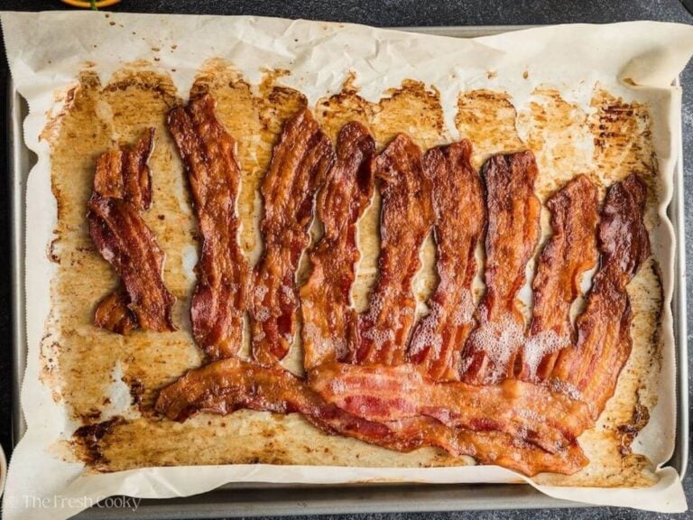 Cooking bacon on parchment paper, until crispy.