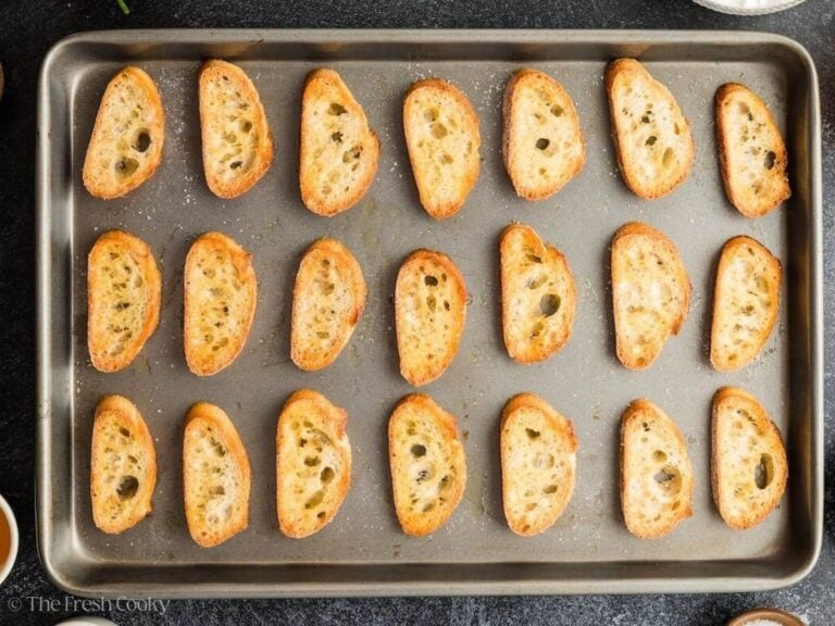 Toasting crostini brushed with olive oil and salt.
