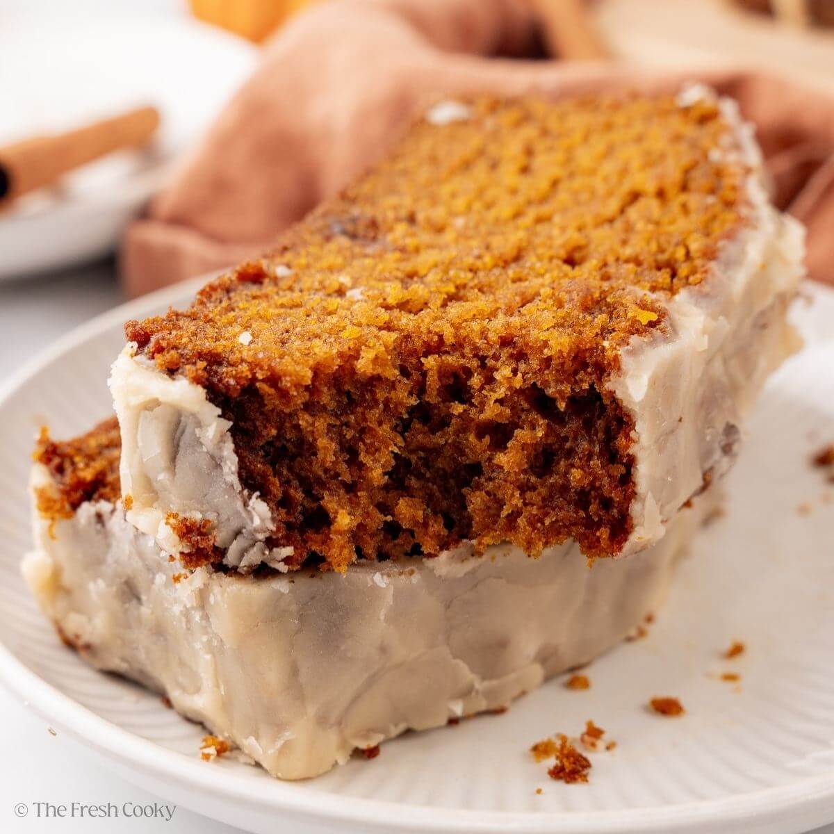 Two slices of pumpkin bread on a plate stacked on top of each other, with one bite missing.