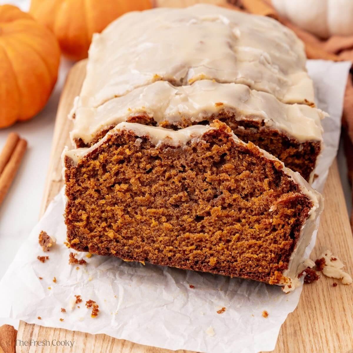 Slice of pumpkin bread leaning against another slice off the end of the loaf.