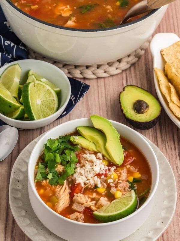 Bowl of chicken tortilla soup with pot behind. 