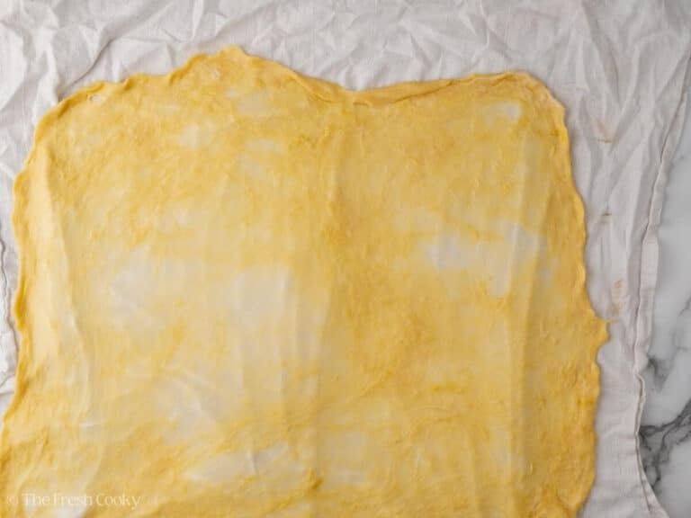 Apple strudel dough stretched out onto a linen.