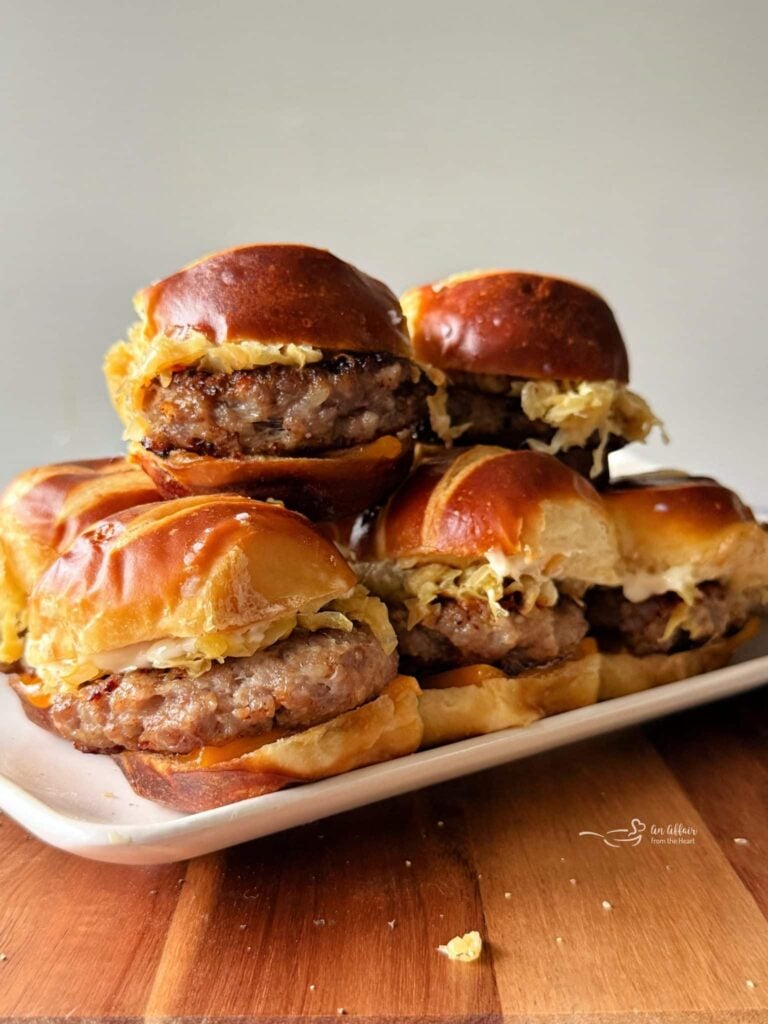 A stack of bratwurst sliders on a tray.