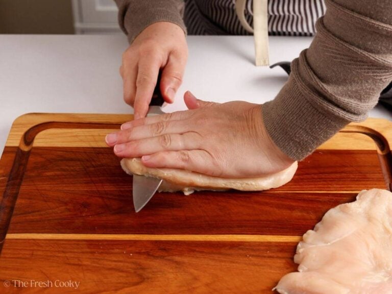 Using a knife to slice the chicken breast in half length wise.