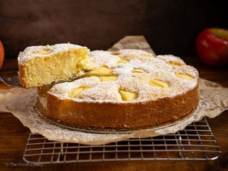 Sunken apple cake with slice being removed.