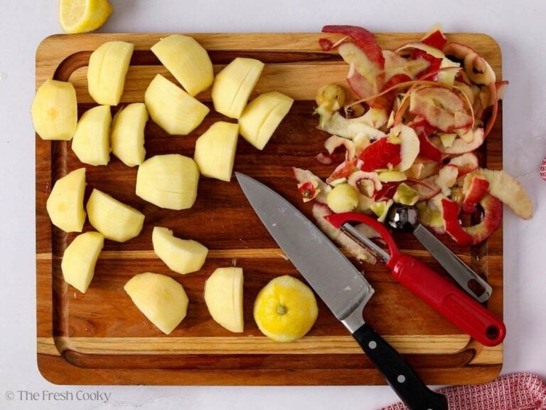 Prepped and sliced apples on a wooden board.