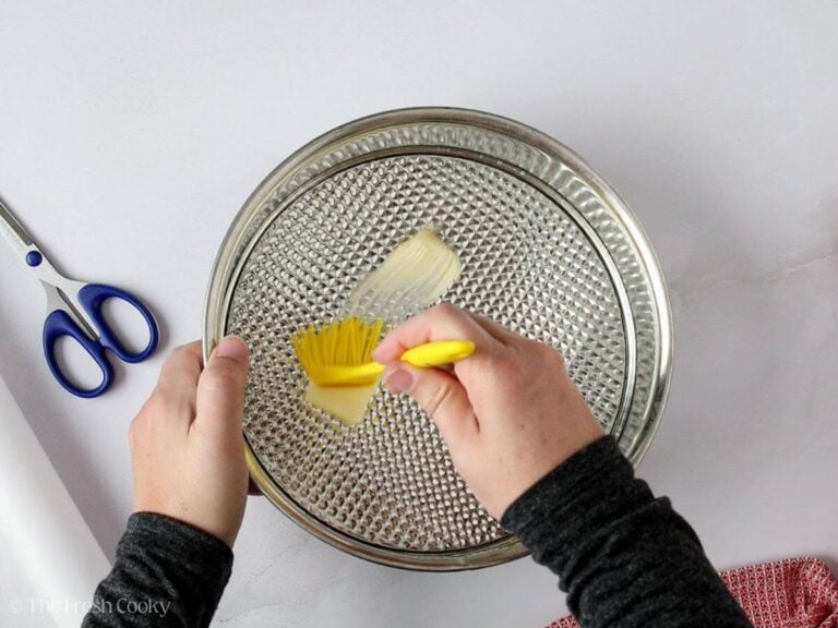 Lining a cake pan with butter.