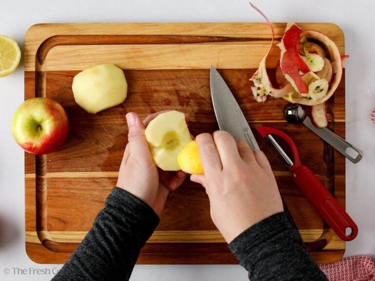Spreading a lemon wedge onto the peeled and cored apples.