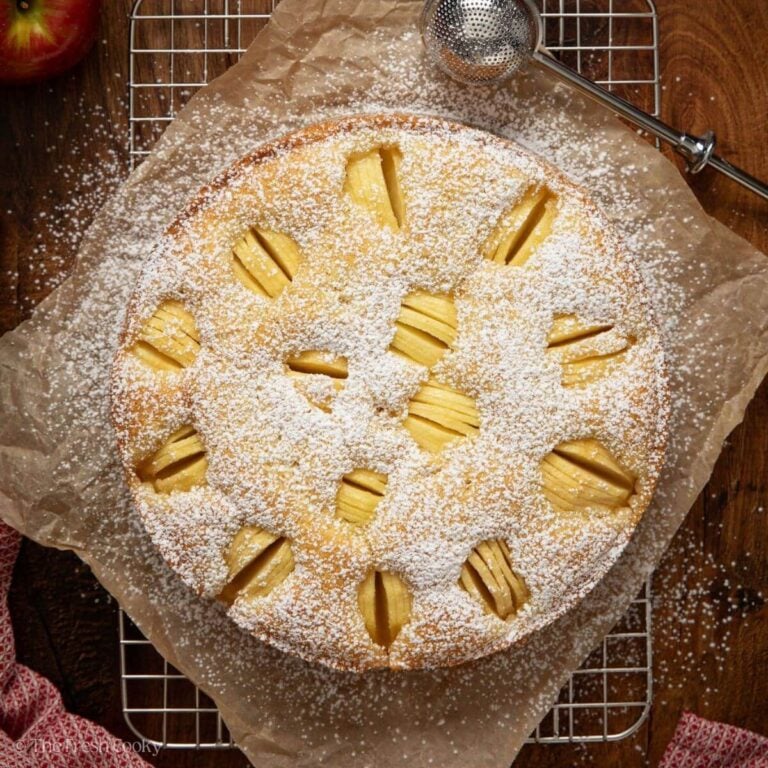 Finished German apple cake on a wire rack with powdered sugar on top.