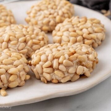 Side view of pignoli cookies served on a plate.