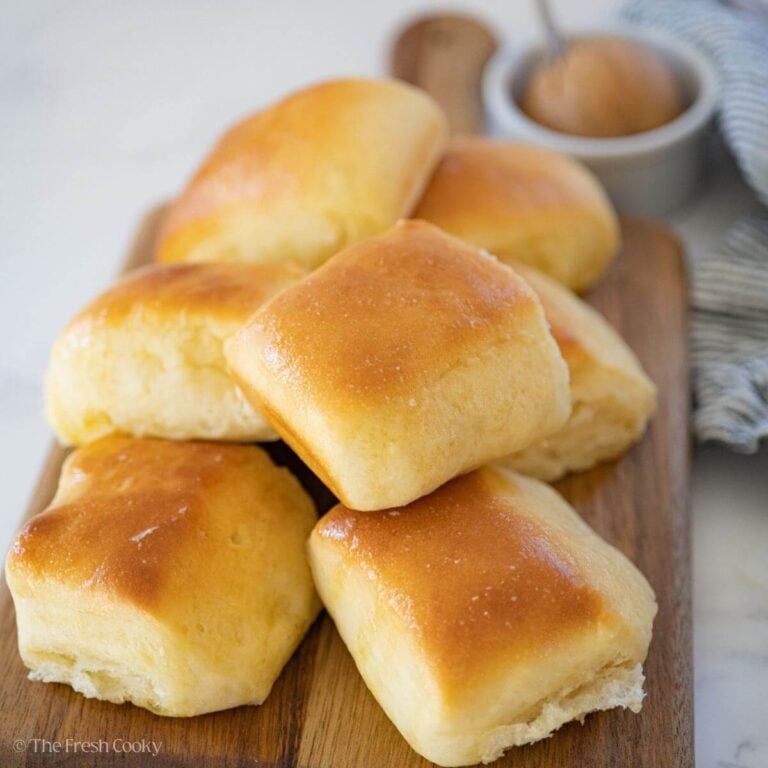 Baked Texas roadhouse rolls stacked on top of each other on a wooden board.