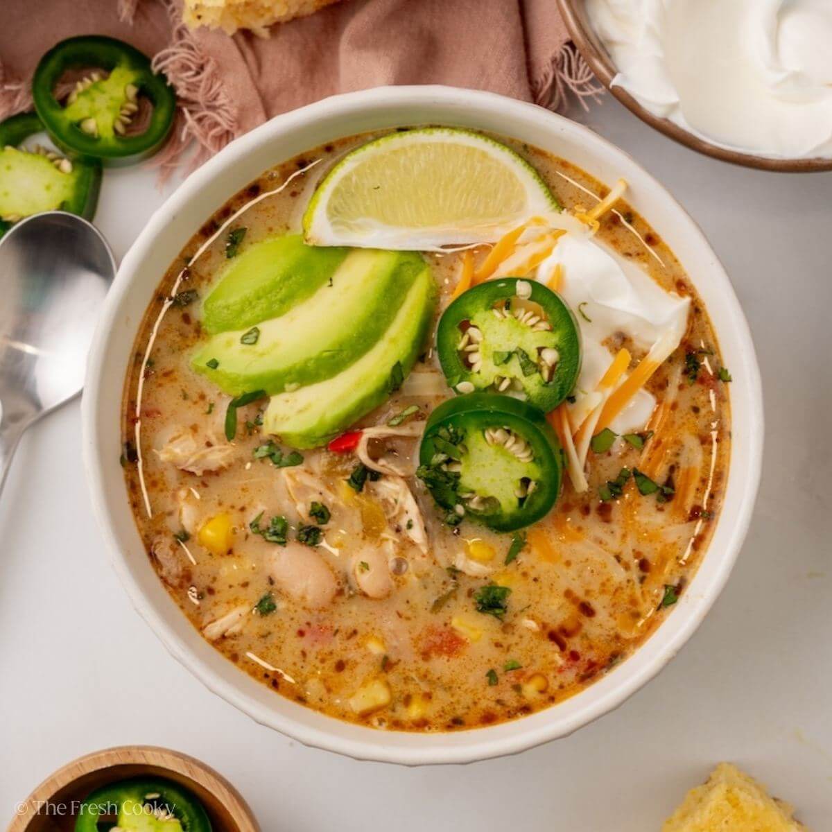 Overhead shot of a bowl of white chicken chili with toppings like jalapeno and avocado.