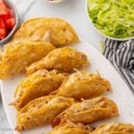 Baked chicken tacos on a platter with toppings.