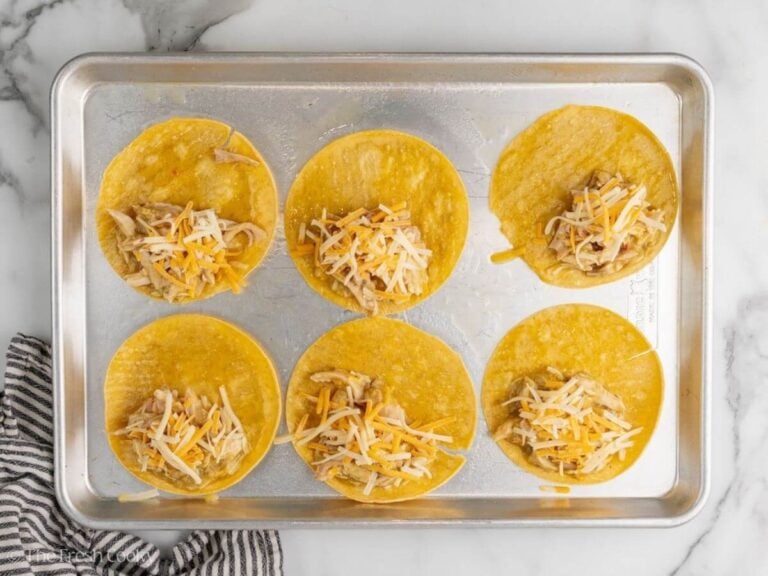 Shredded chicken mixture and shredded cheese placed on each corn tortilla.