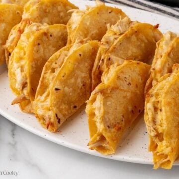 Baked chicken tacos leaning on each other on a serving platter.
