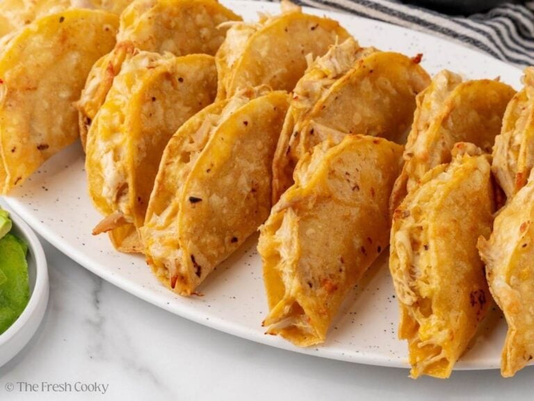 Baked chicken tacos leaning on each other on a serving platter.