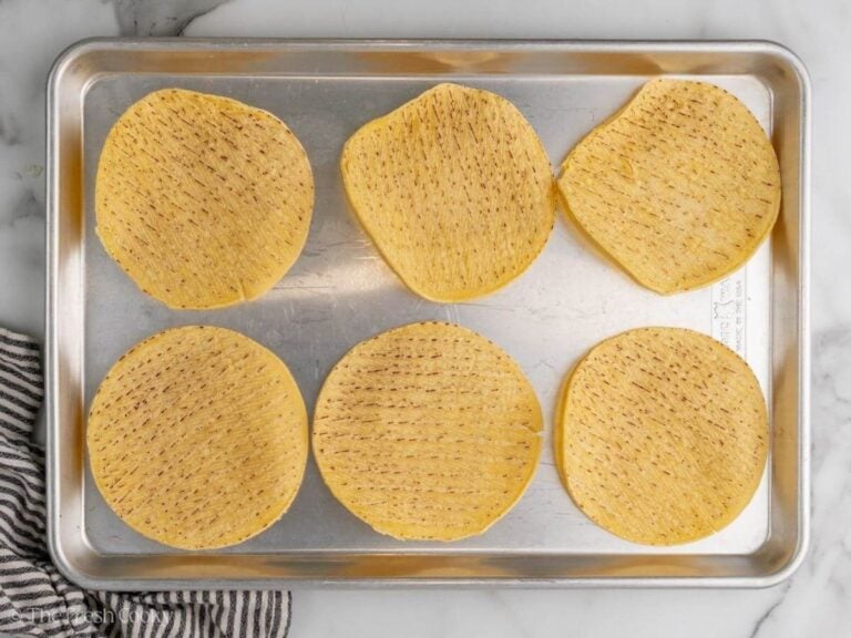 Corn tortillas laid out on a sheet pan.