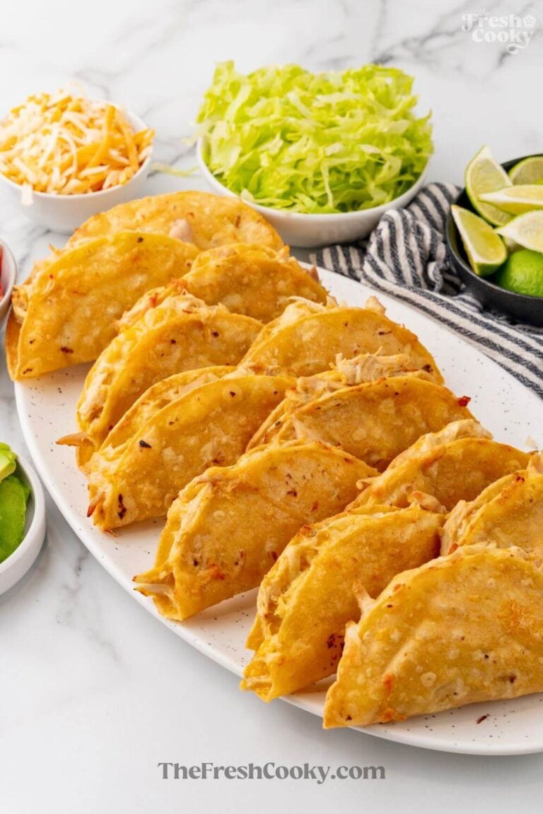 Platter of crispy baked chicken tacos with toppings to serve, for Pinterest.