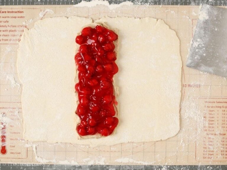 Cherry filling on top of the cream cheese layer on the dough.