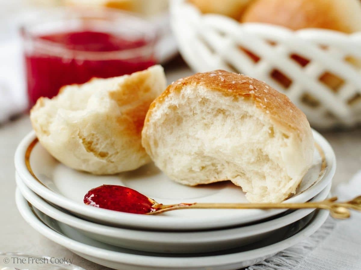 Close-up of a yeast roll, soft, warm and fluffy on a plate, with a spoon of jam.