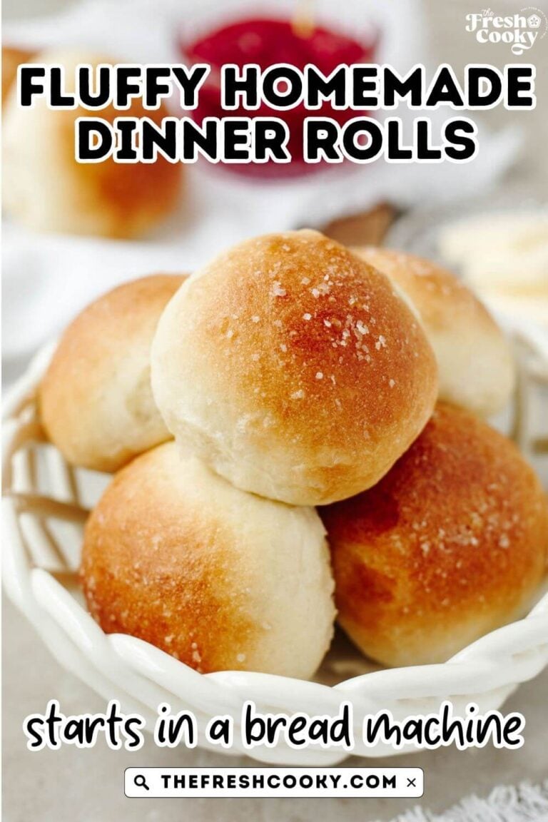 A pretty white, woven basket with fluffy golden yeast rolls inside, to pin.