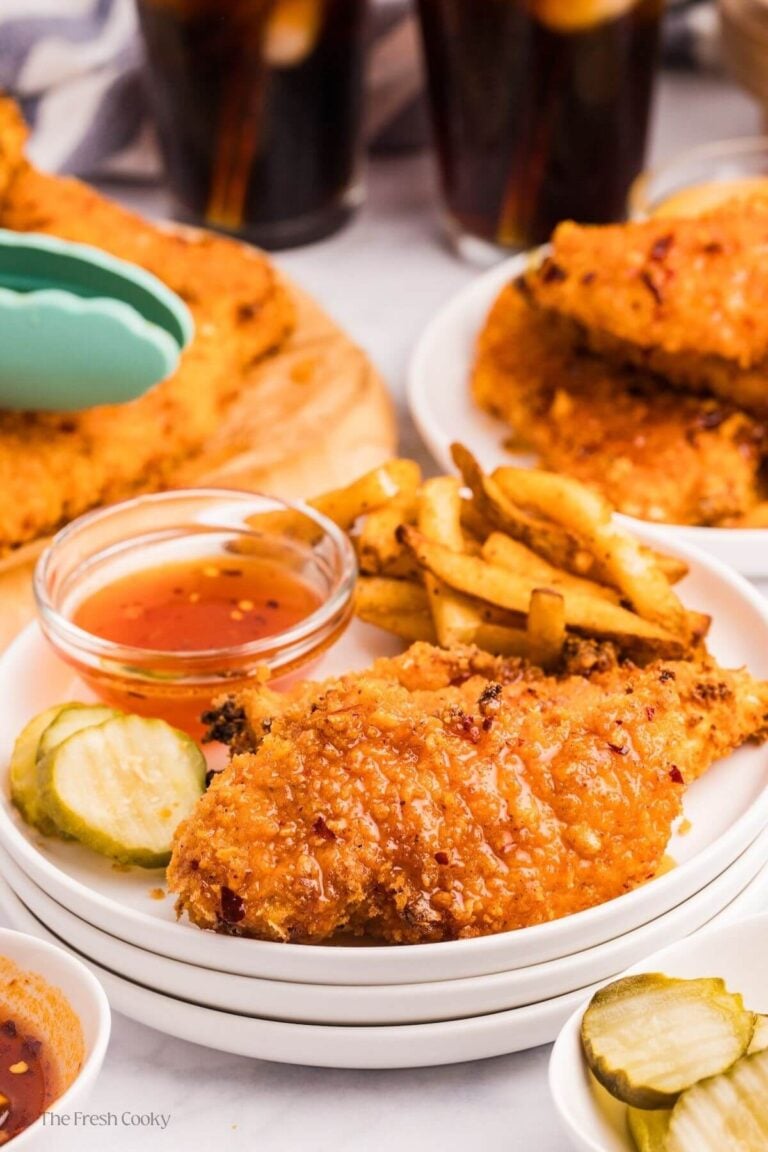 Hot honey chicken tenders on a plate with fries on side.