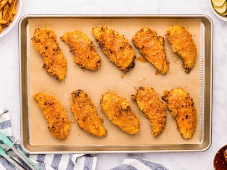 Chicken tenders on a sheet pan lined with parchment paper with hot honey on top.