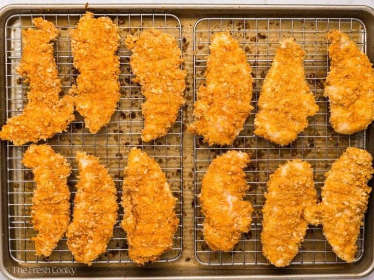 Baked chicken tenders on a sheet pan lined with wire racks.