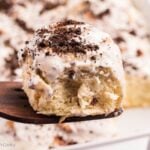 Oreo cinnamon roll on a wooden spatula with more rolls in the background.