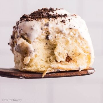 Side view of an Oreo cinnamon roll on a wooden spatula.