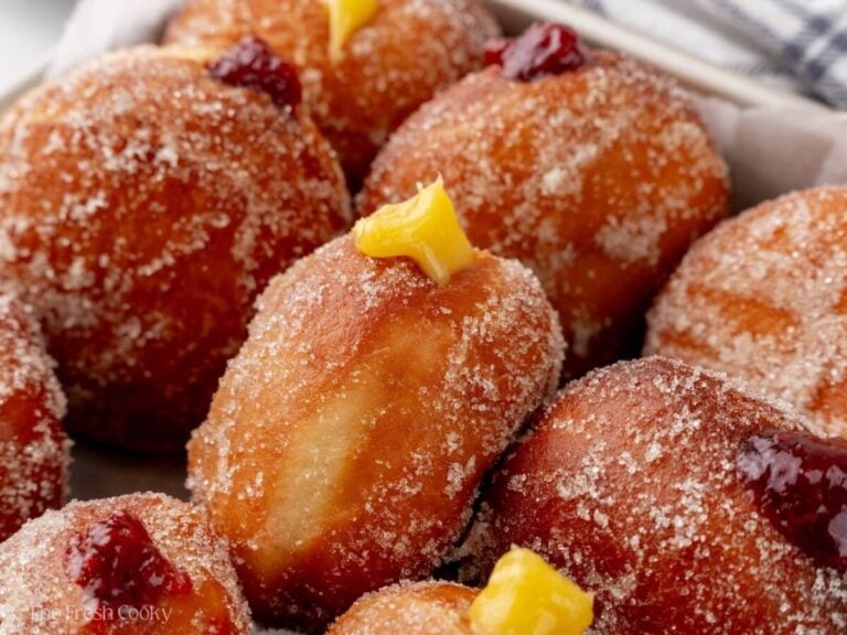 Paczki donuts lined up, all coated in sugar and will filling sticking out a bit.