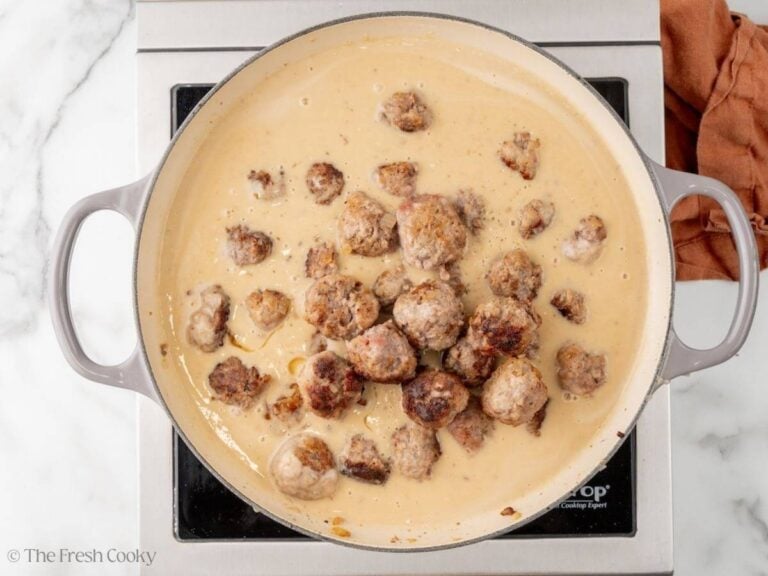 Meatballs added back into the sauce in a skillet.