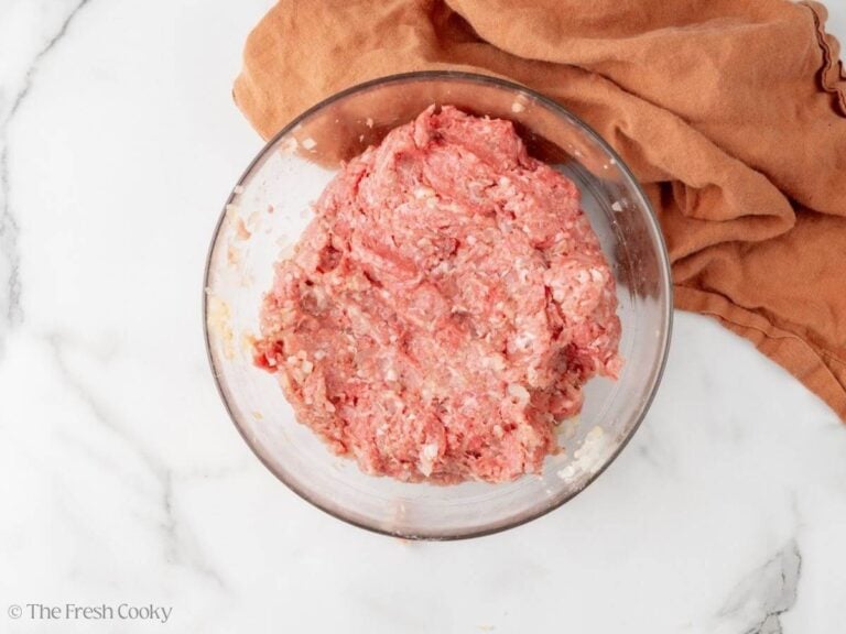 Ground meet mixed with onion and spices in a bowl.
