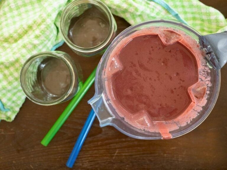 Blended vegetable and fruit smoothie next to two empty jars.