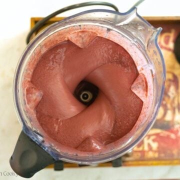 Blending the fruit and vegetable smoothie in a large blender.