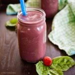 Fruit and veggie smoothie in a large jar with a blue straw.