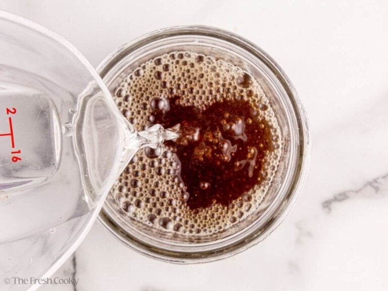 Filtered water is added to the SCOBY tea mixture in a glass jar.