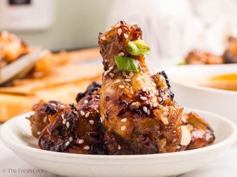 Sticky chicken wings served on a plate with one drummette sticking up.