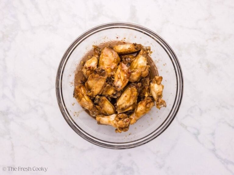 Sticky wing sauce added to the cooked wings in a mixing bowl.