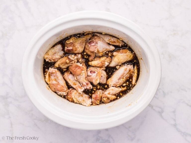 Wings added to the sauce in a slow cooker.