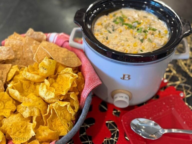 Corn dip in a crock pot with a basket of chips.