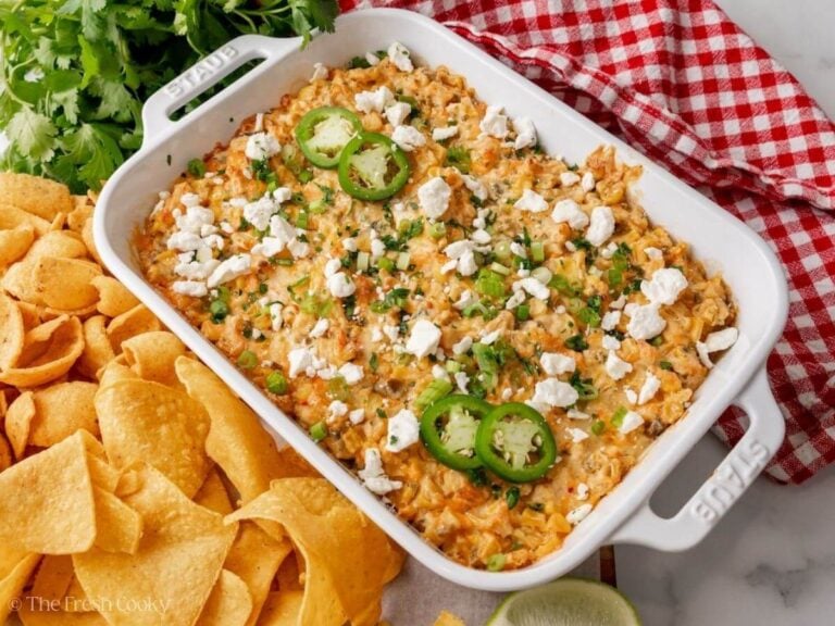 Baked Mexican street corn dip in a white baking dish, garnished with cotija cheese, jalapeño, cilantro and green onions.