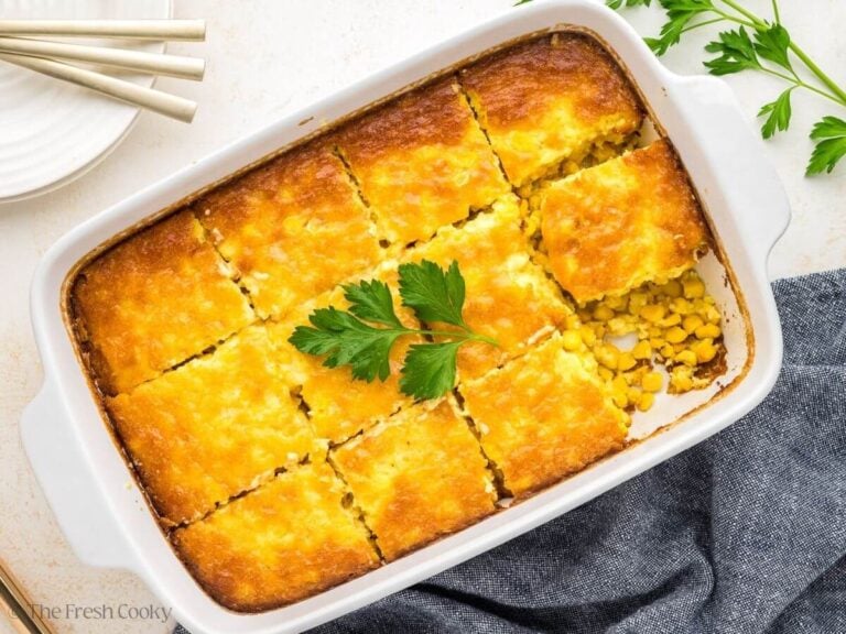 Corn pudding casserole sliced into square pieces in a baking dish.