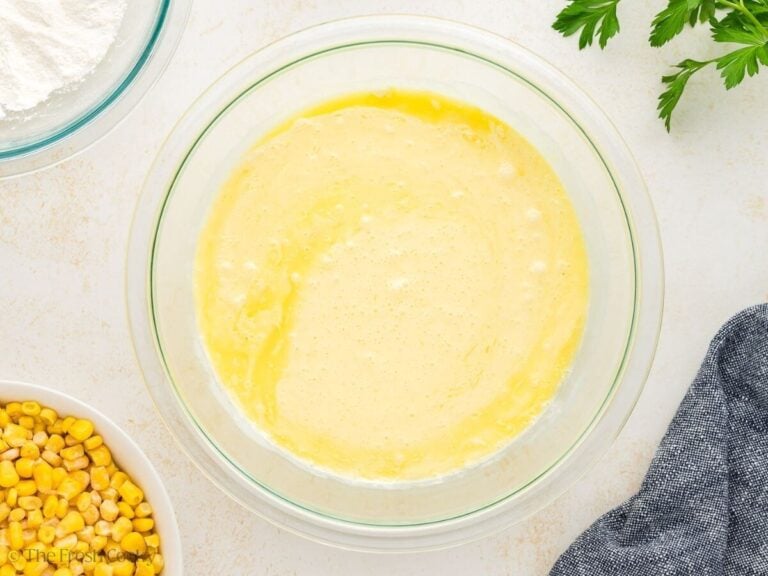 Eggs, melted butter, and cream whisked together in a mixing bowl.