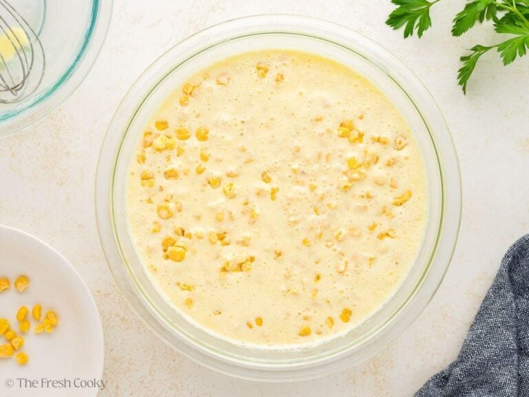 Corn stirred into corn casserole batter in a mixing bowl.