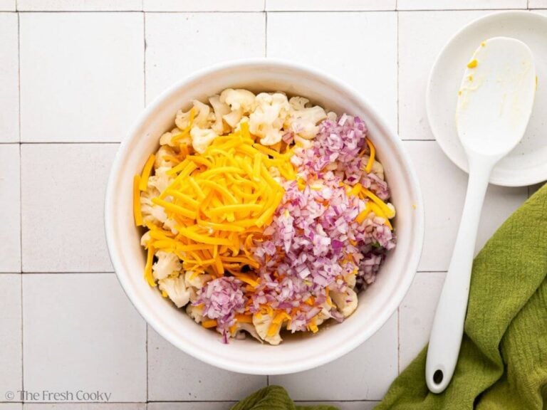 Broccoli, cauliflower, cheese and red onion added to the bowl of dressing.